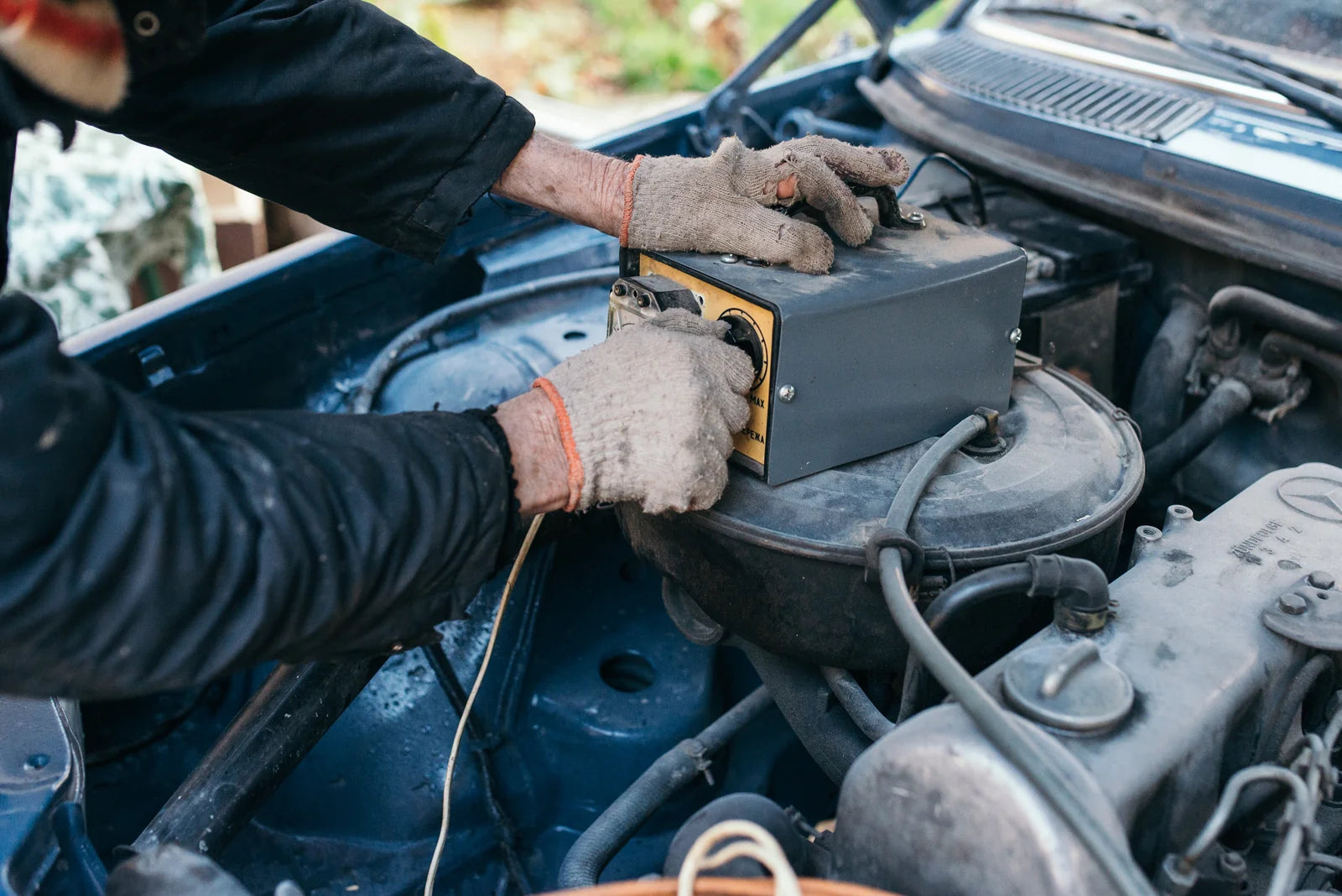 Mechanic checking a car battery while diagnosing slow cranking