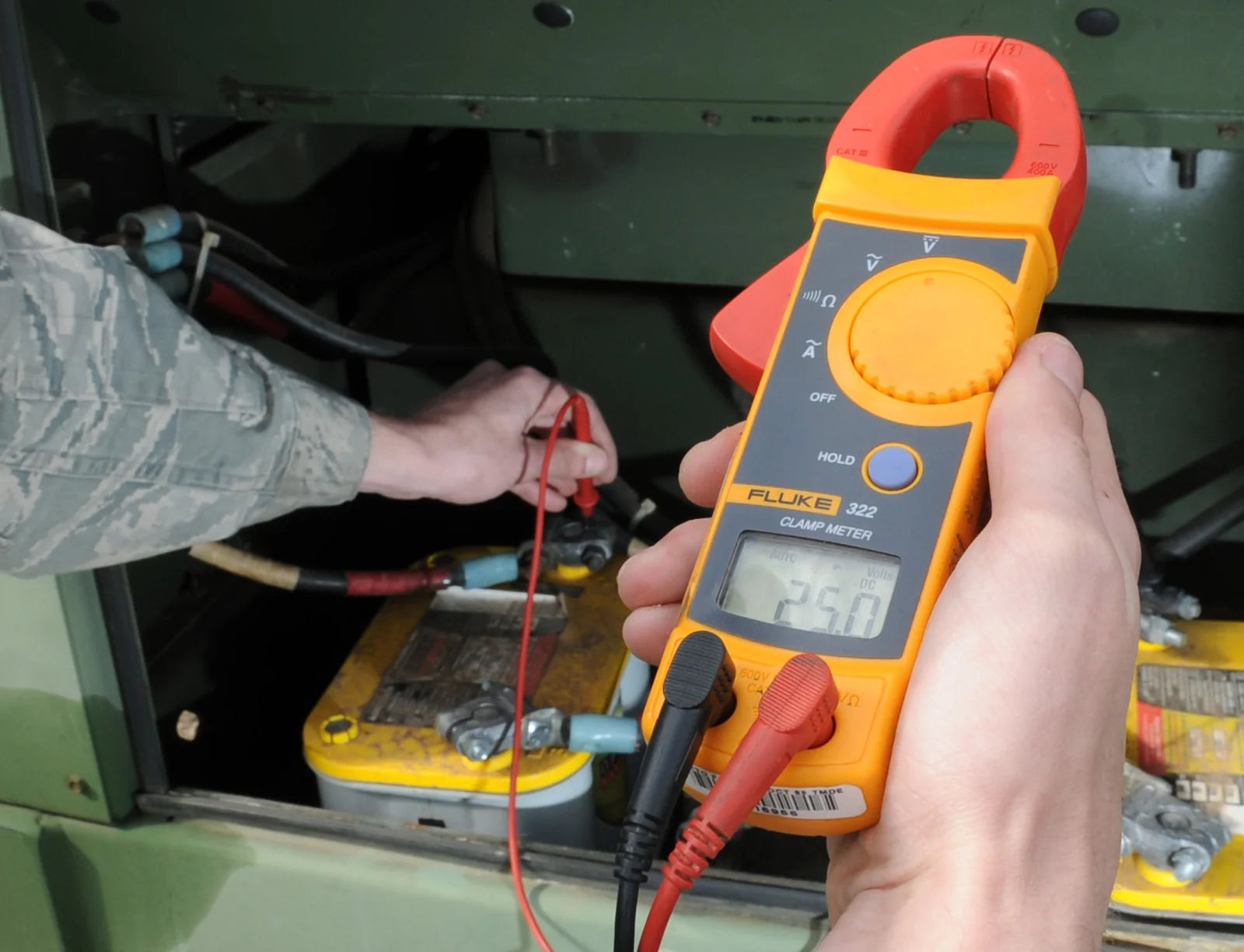 Technician measuring battery voltage before a CCA load test
